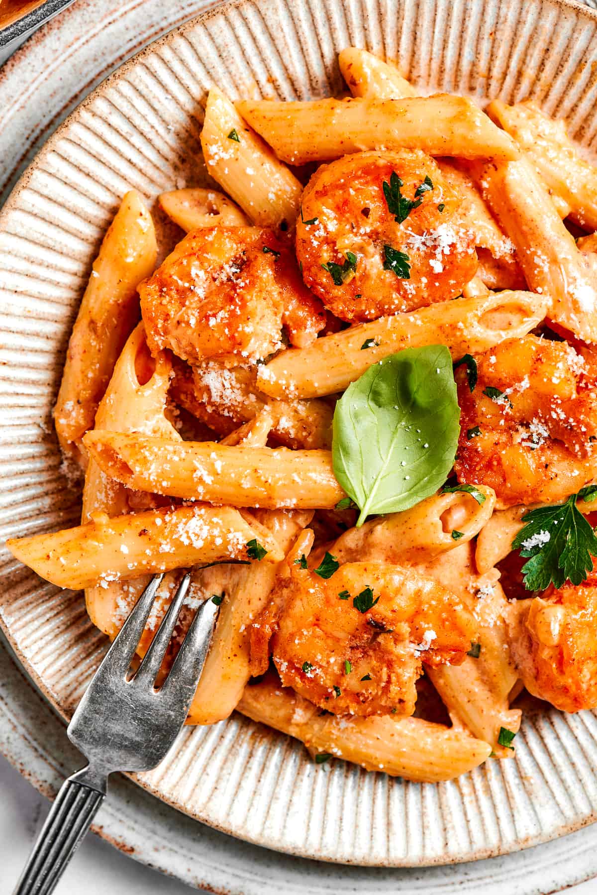 A close up of red cajun shrimp pasta with a fork.