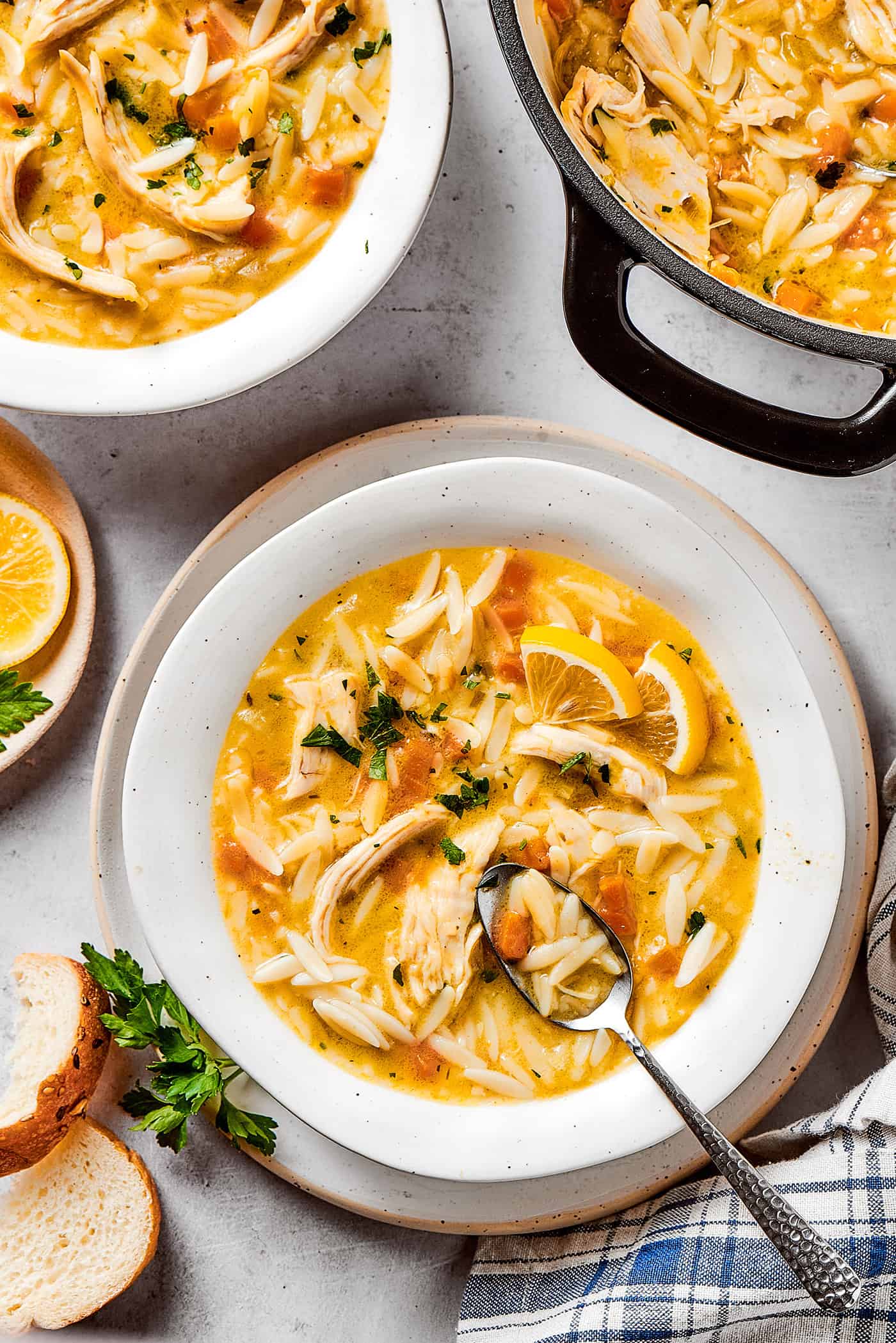 overhead photo of bowls and a pot of chicken soup with lemon and orzo