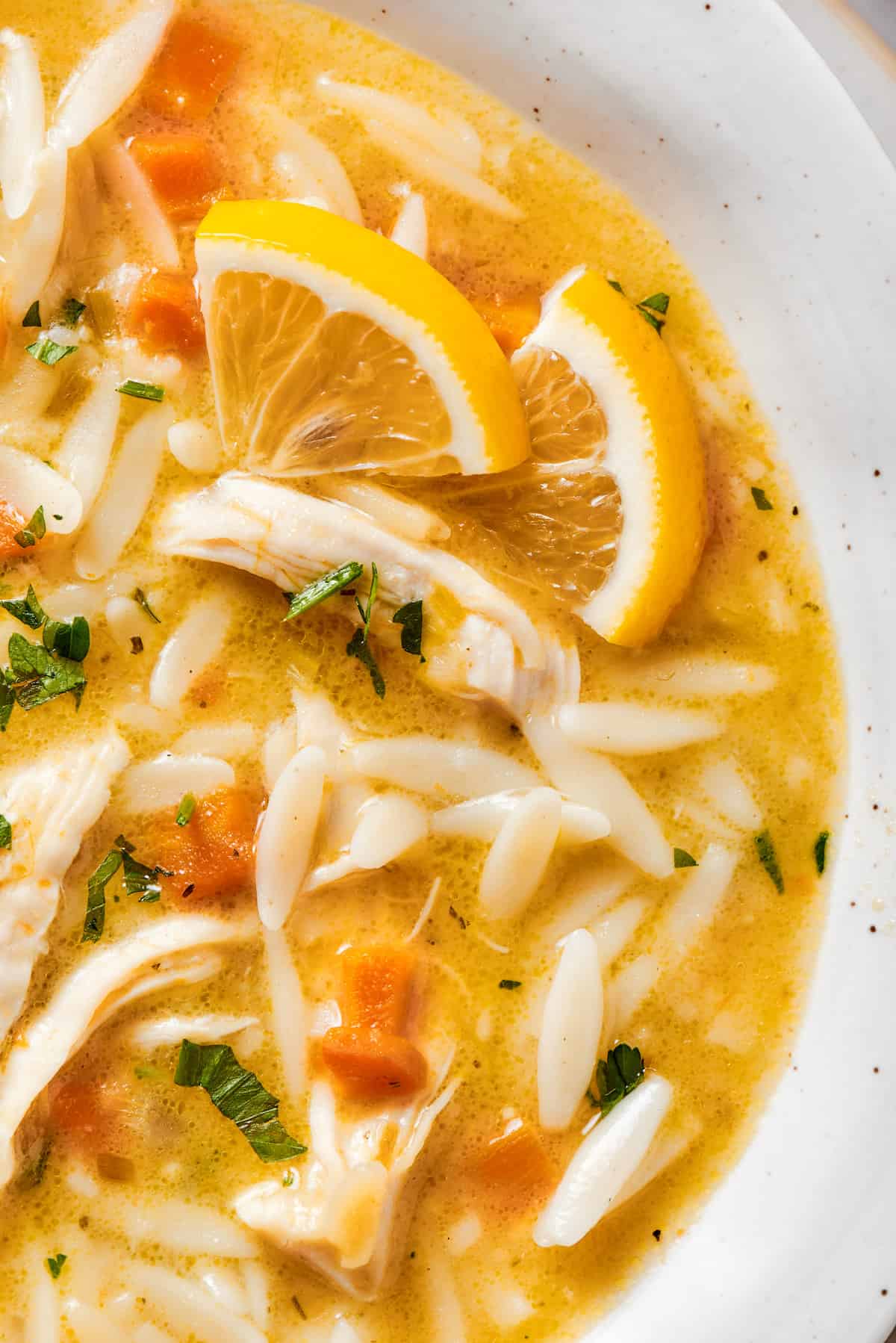 a close-up overhead photo of lemon soup with chicken and orzo pasta