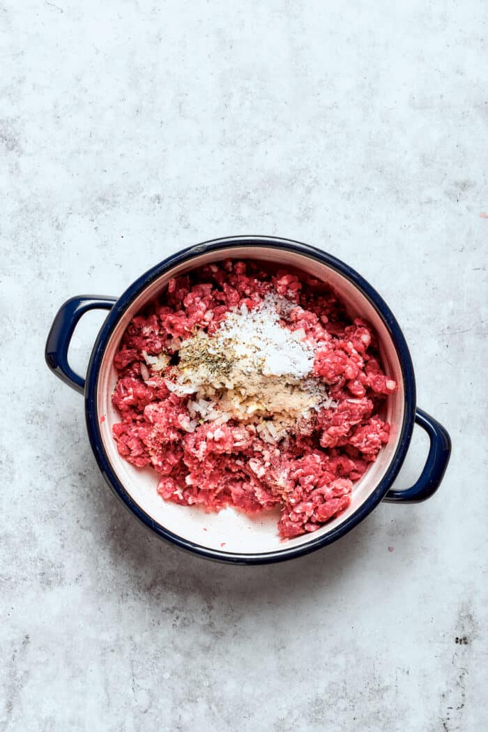 Blend two favorites to make this Pizza Burger recipe! Juicy beef patties are topped with tangy marinara, pepperoni, mozzarella & fresh basil. The meat for pizza burgers is mixed with seasonings in a pot.