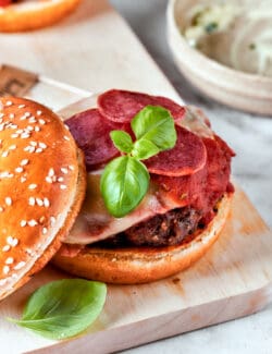 Pepperoni and fresh basil top a pizza burger patty.