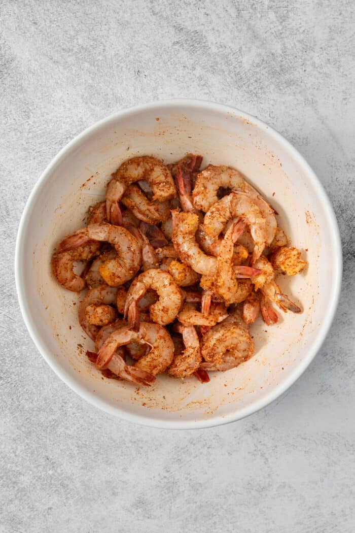 A bowl of shrimp with seasoning.