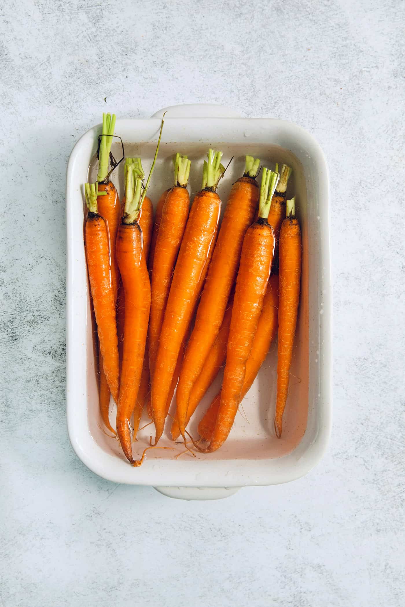 whole carrots in a pan of water