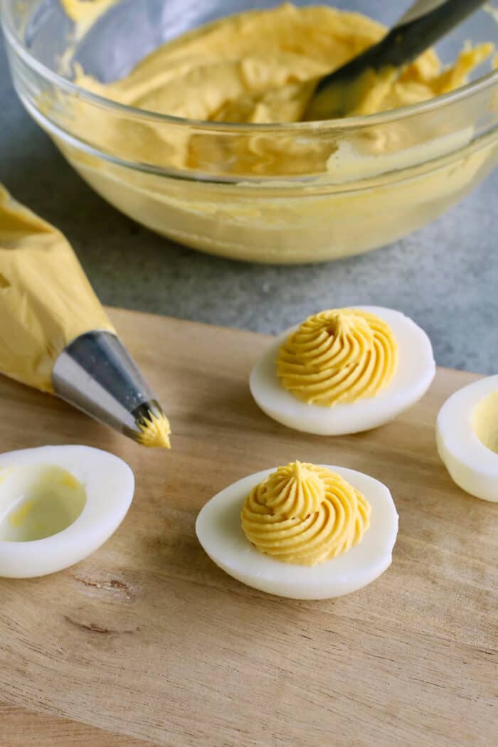 Deviled egg filling is piped into hard boiled egg whites.