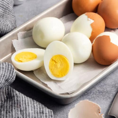 hard boiled eggs on a rimmed pan, some are peeled and cut in half
