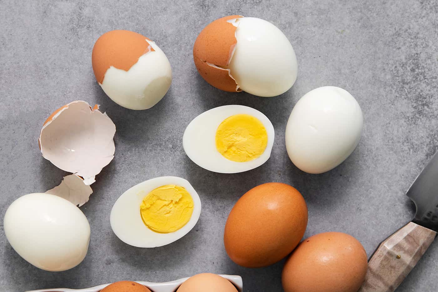 hard boiled eggs on a gray counter, some are peeled and cut in half