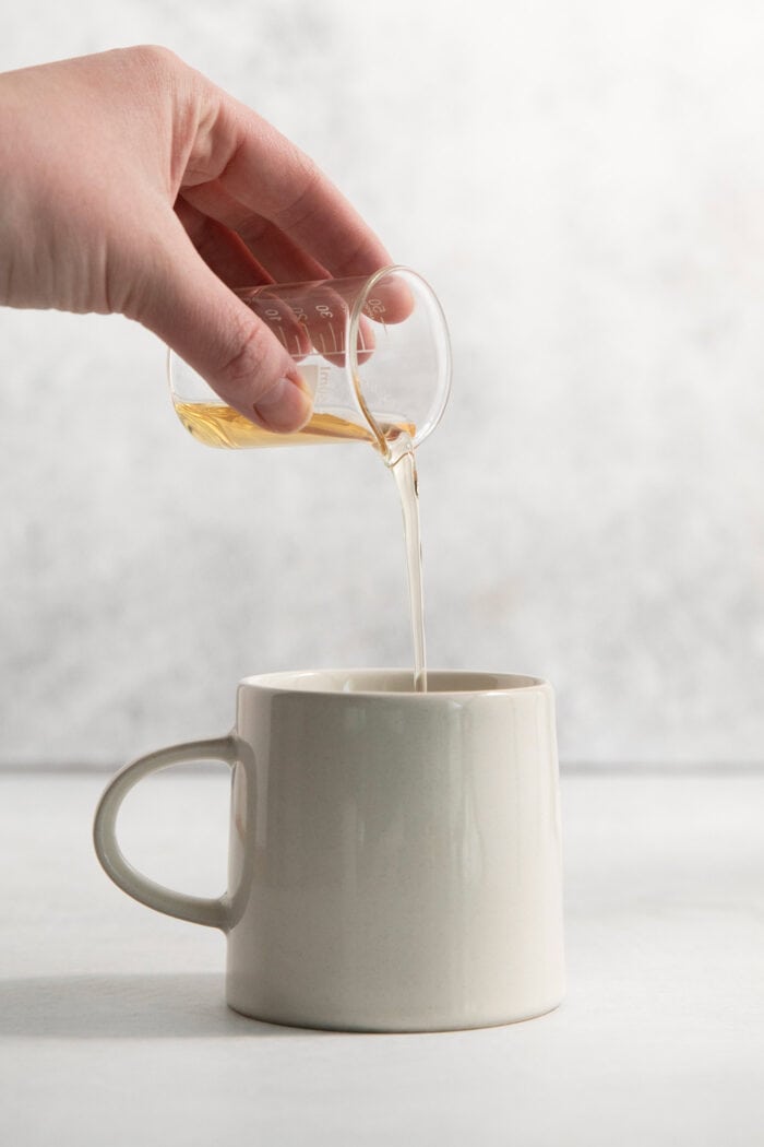 Lavender simple syrup is poured into a mug.