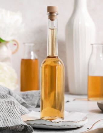 A glass bottle full of lavender simple syrup that's stopped with a cork.