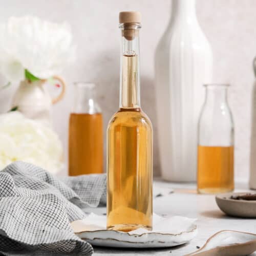 A glass bottle full of lavender simple syrup that's stopped with a cork.