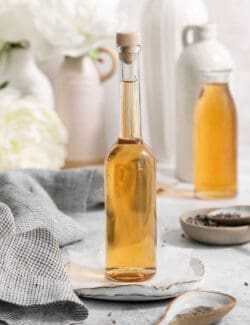 A glass bottle full of lavender simple syrup that's stopped with a cork.