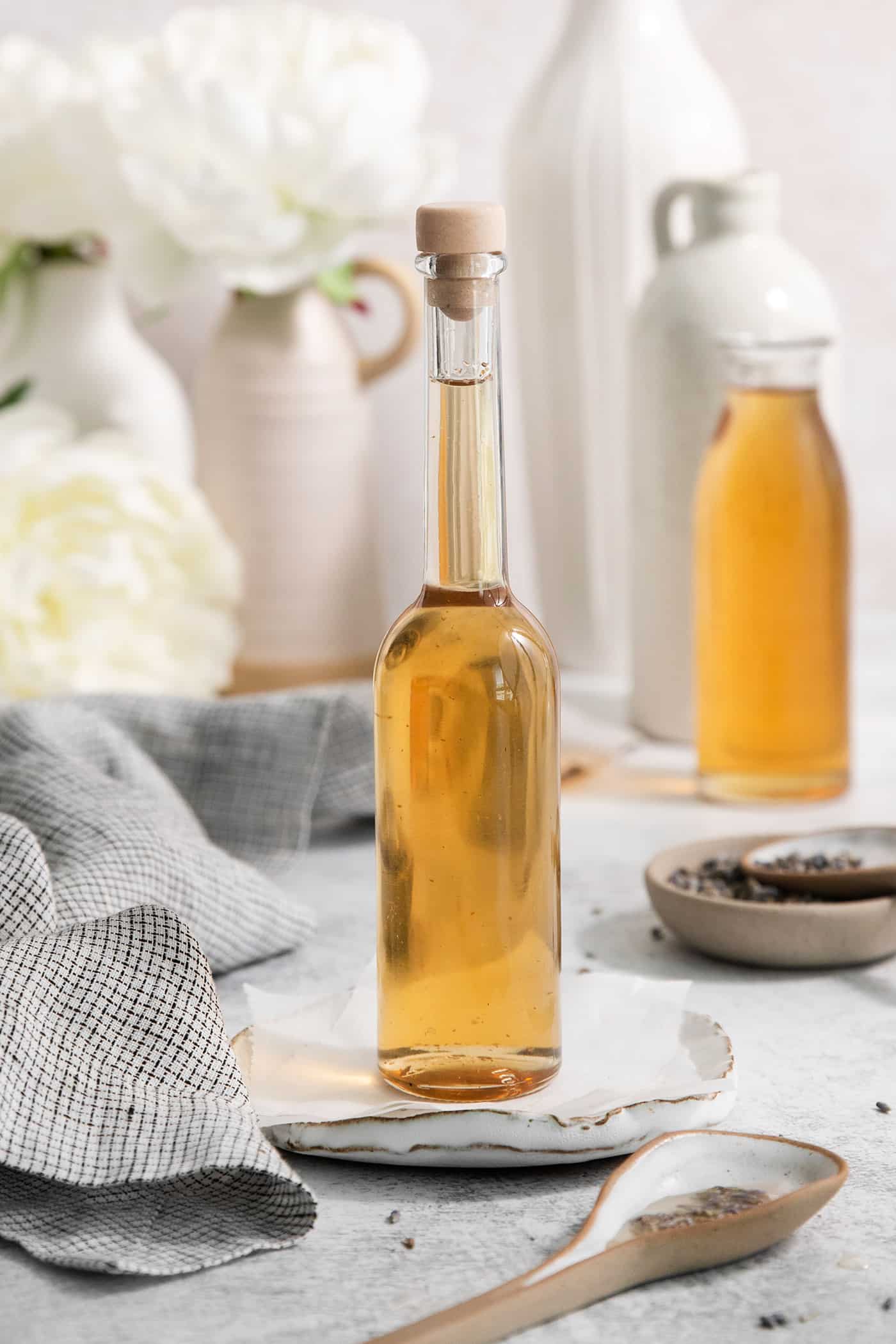A glass bottle full of lavender simple syrup that's stopped with a cork.