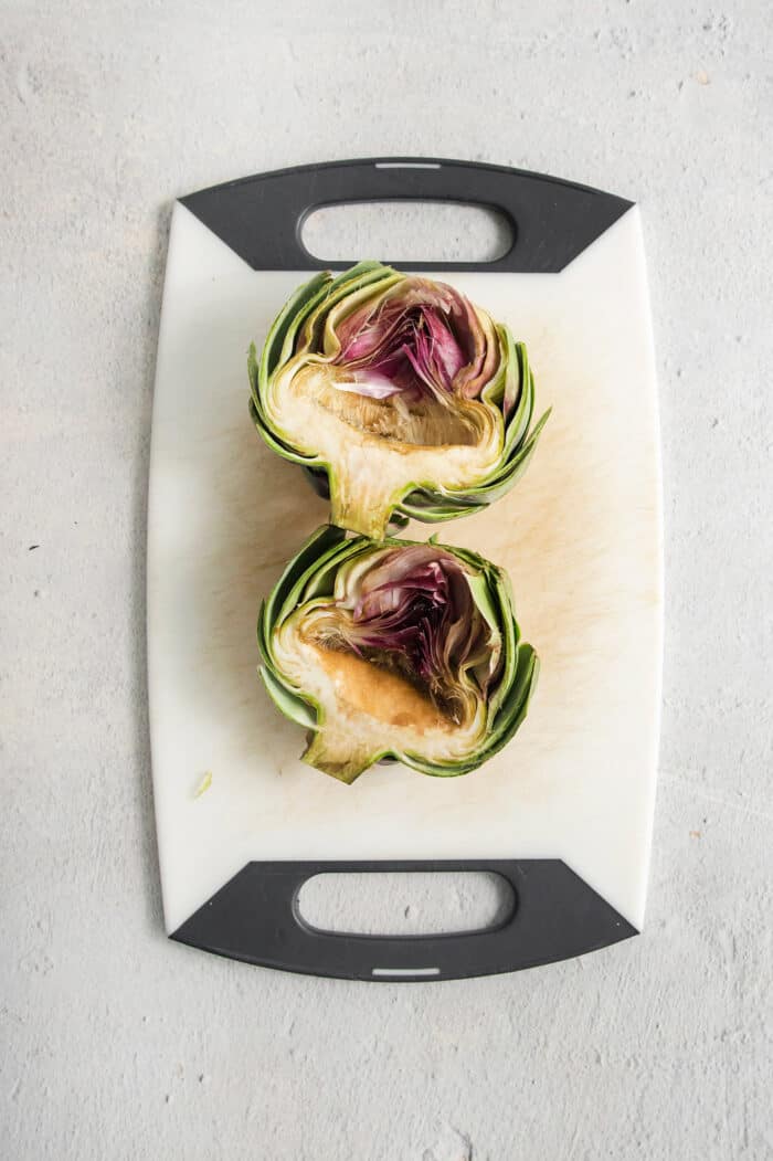 an artichoke on a cutting board with the fuzzy choke scooped out