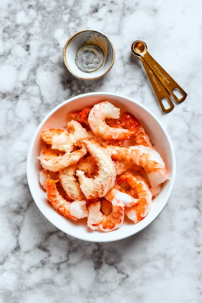 Shrimp marinates in a bowl.