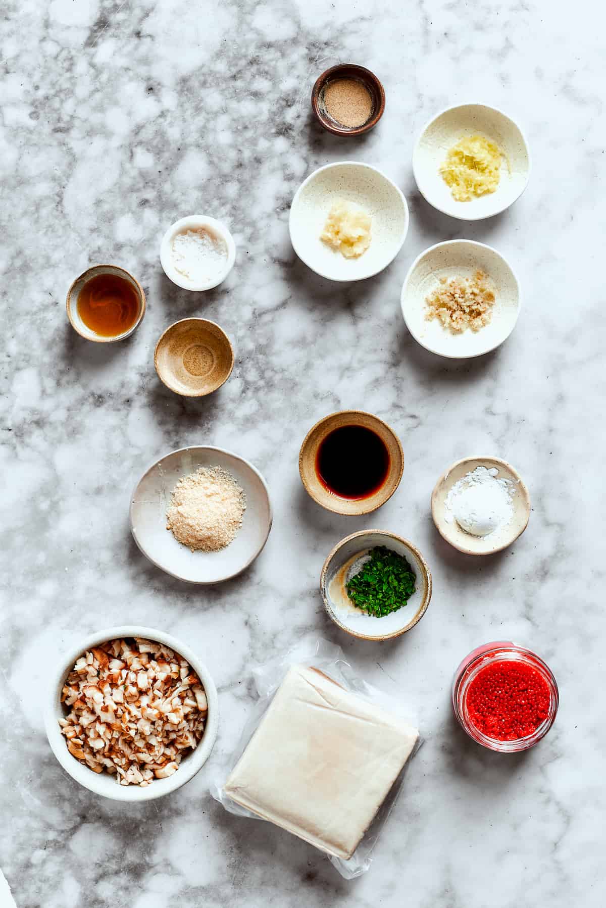 The ingredients for shrimp shumai are shown portioned out: soy sauce, vinegar, salt and pepper, lemongrass, ginger, garlic, shrimp, mushrooms.