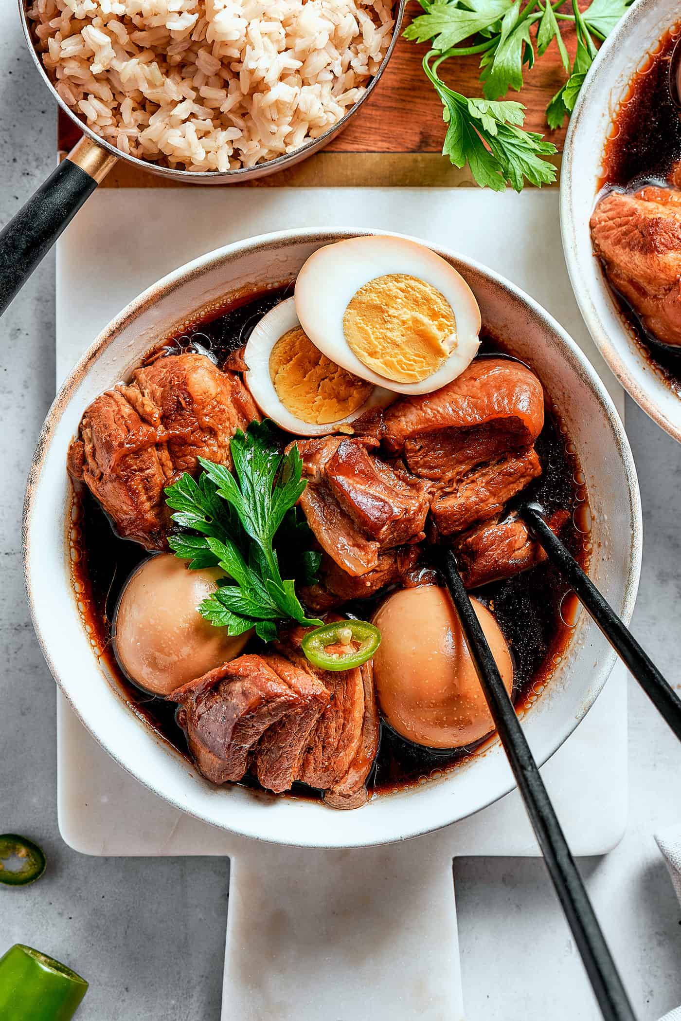 overhead photo of thit kho in a bowl with chopsticks, with one hardboiled egg cut in half