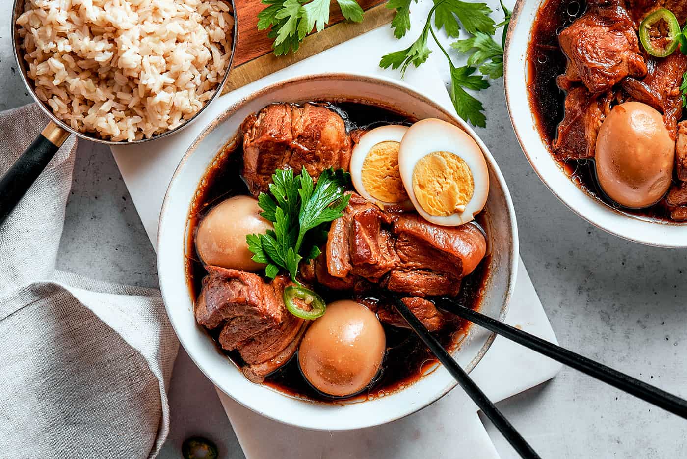 overhead photo of thit kho in a bowl with chopsticks, with one hardboiled egg cut in half