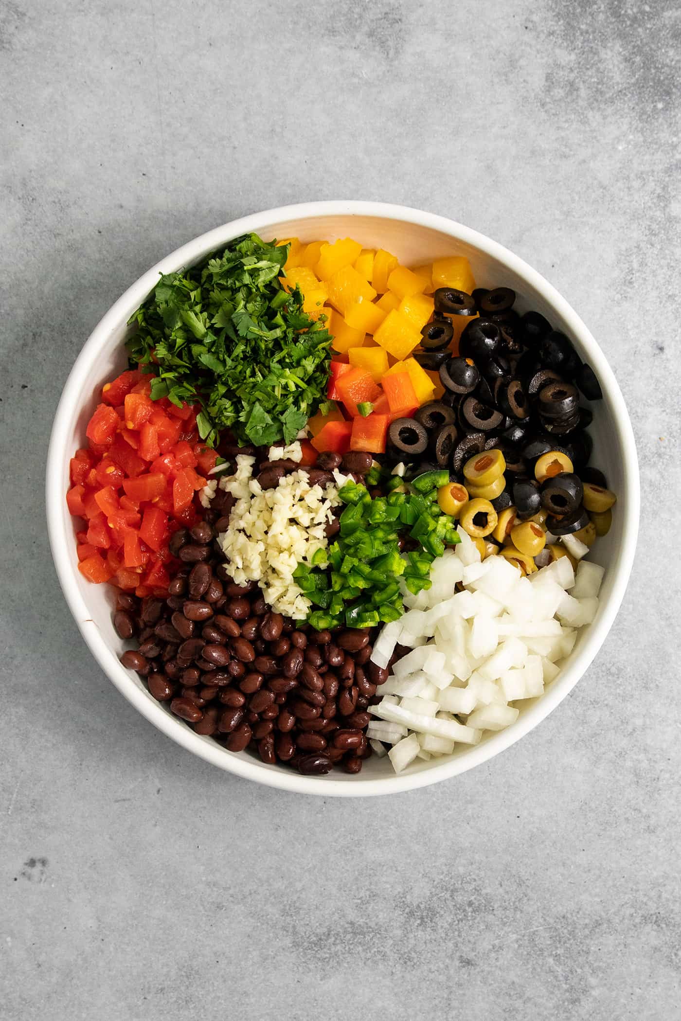 Black bean salsa components are added to a bowl to be mixed together.
