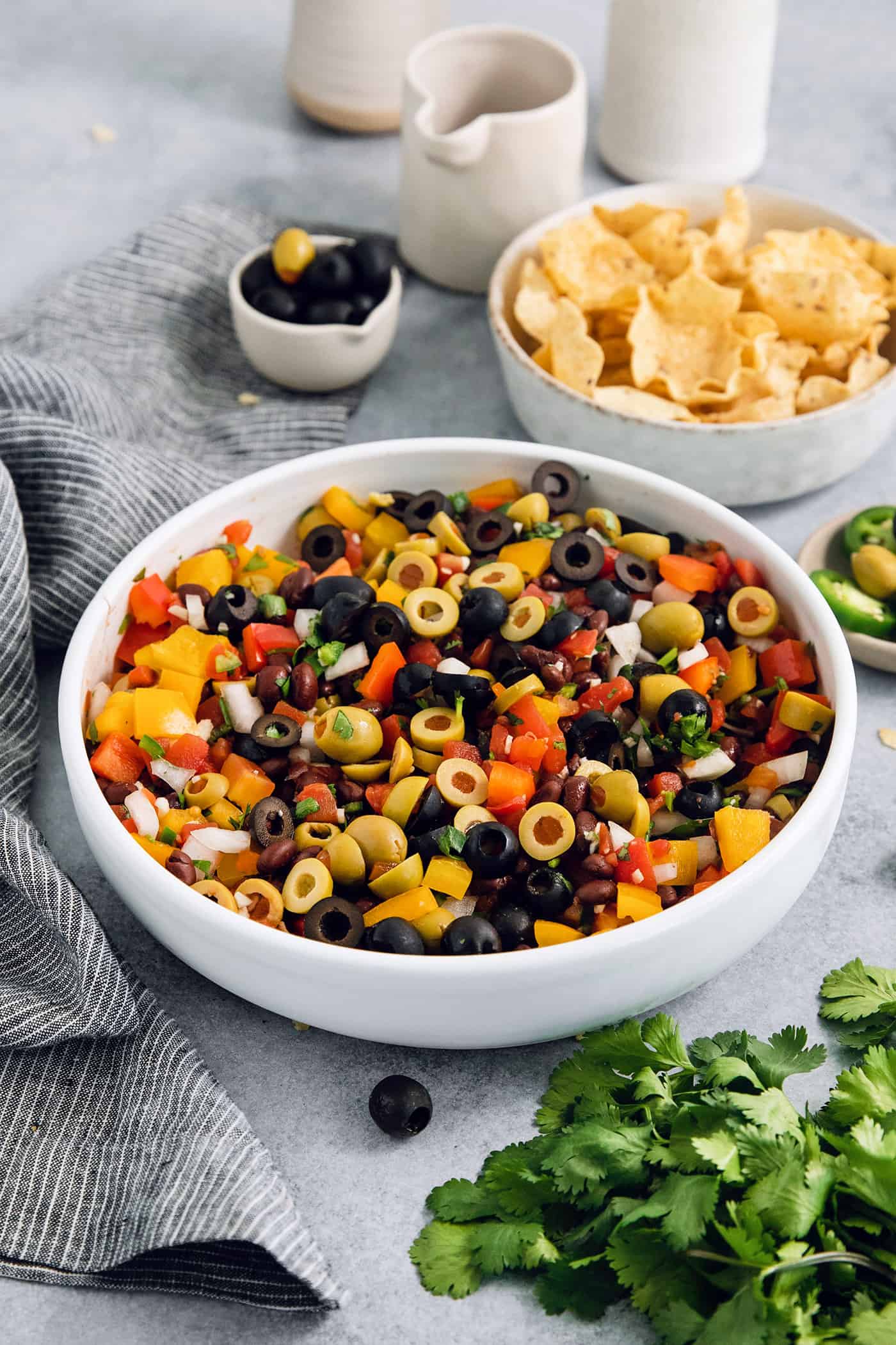 A bowl of black bean salsa on a table with a bowl of chips.