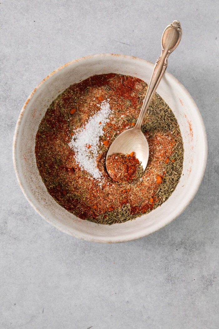 dried spices and herbs in a bowl, with a spoon