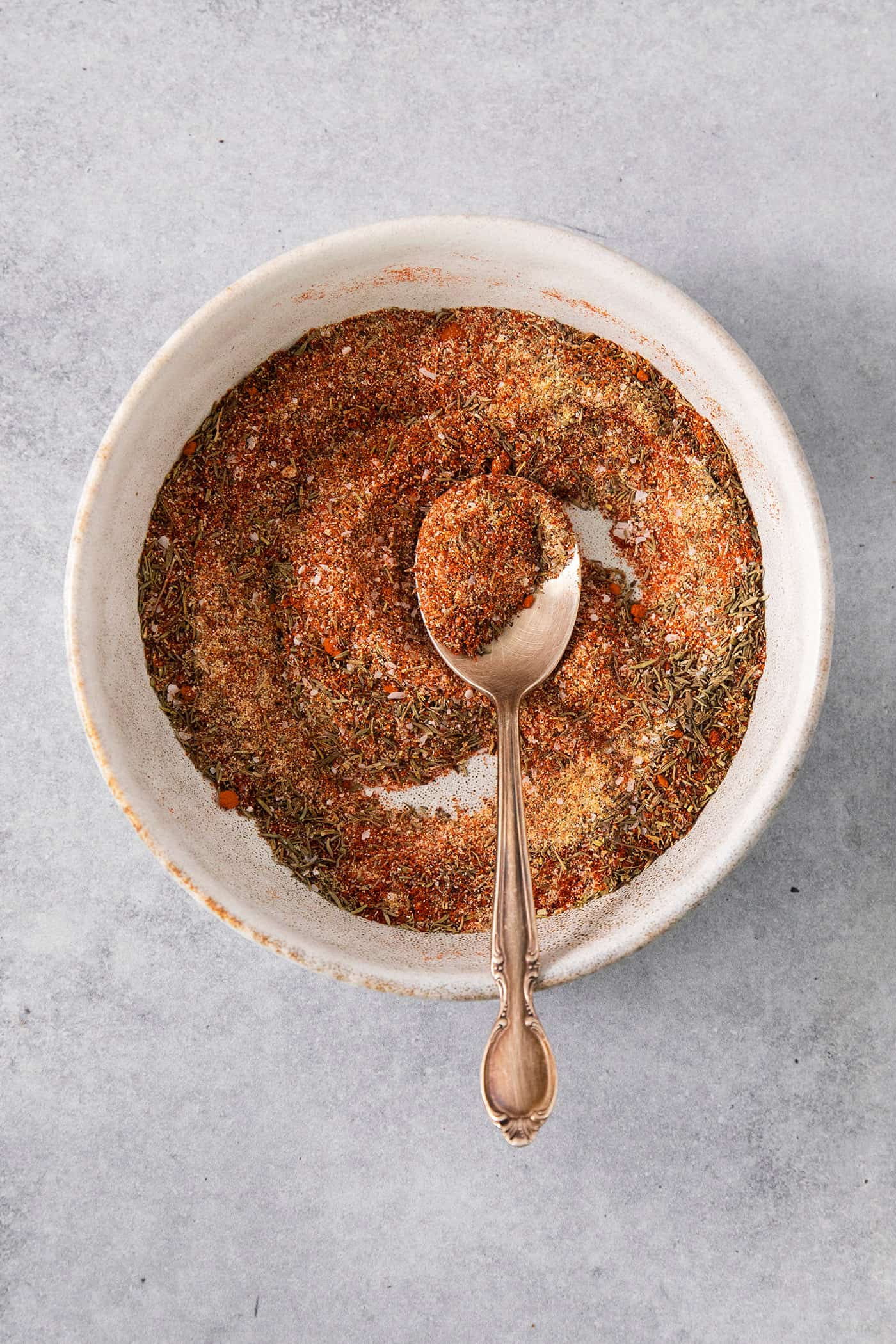 dried spices and herbs in a bowl, with a spoon
