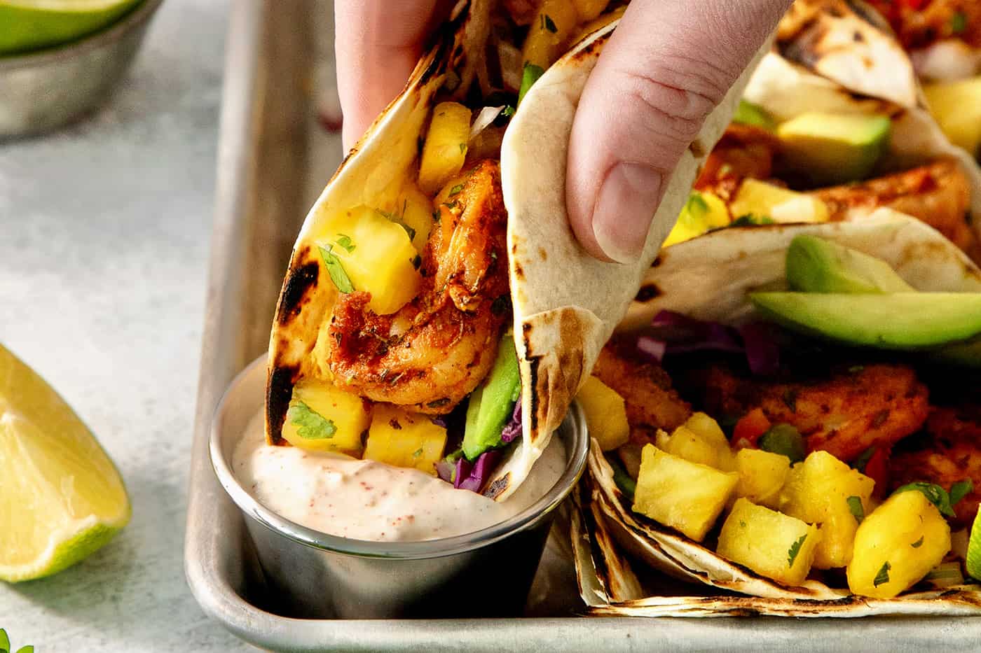 A hand lifts up a perfectly assembled blackened shrimp taco.