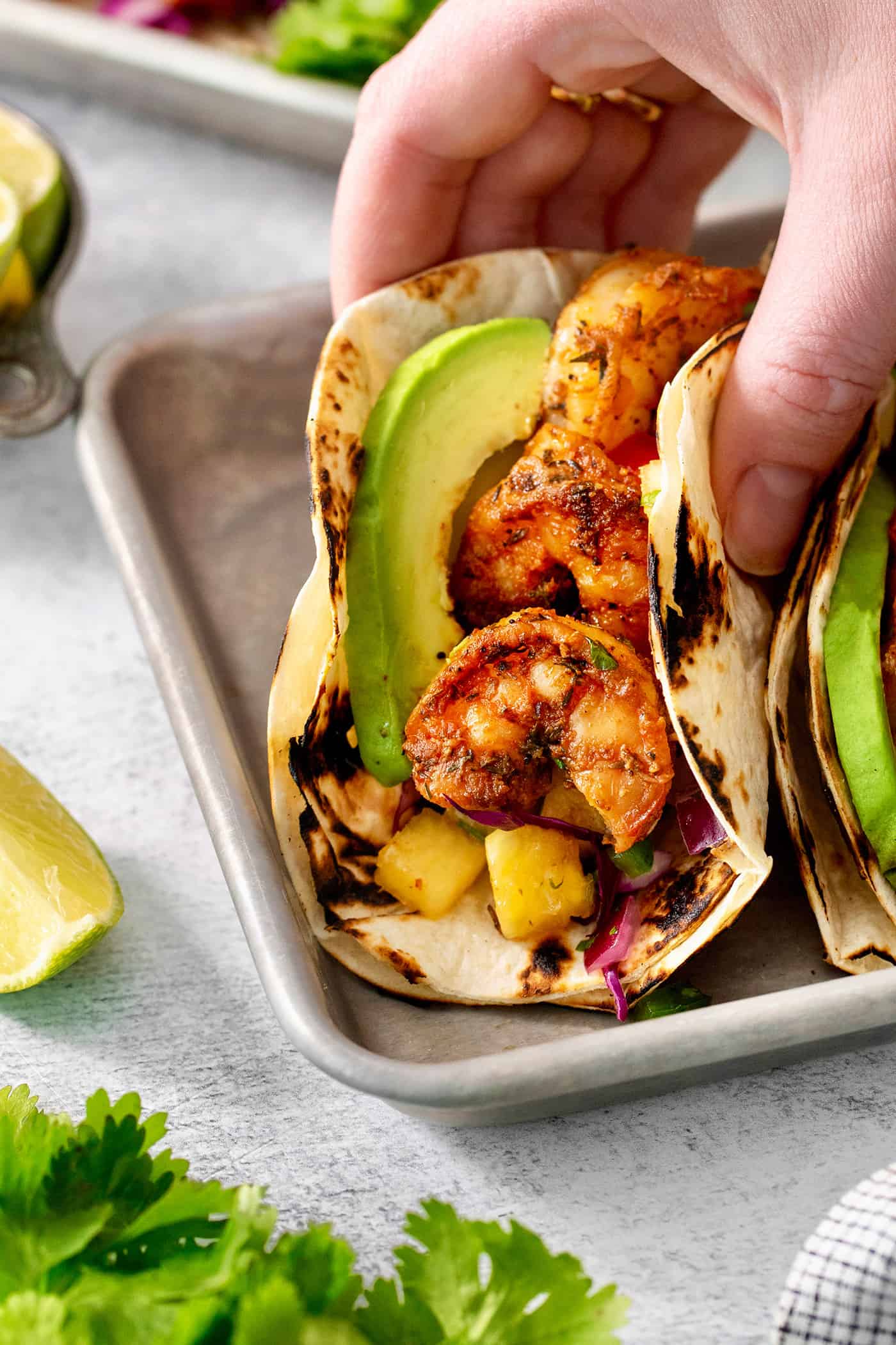 A hand lifts up a perfectly assembled blackened shrimp taco.