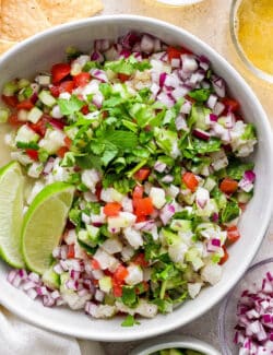 A bowl of classic ceviche with lime wedges.