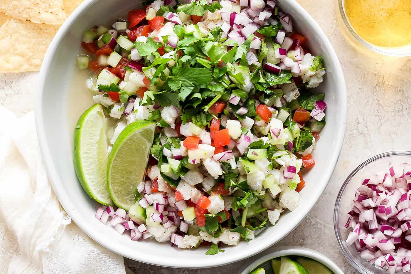 A bowl of classic ceviche with lime wedges.