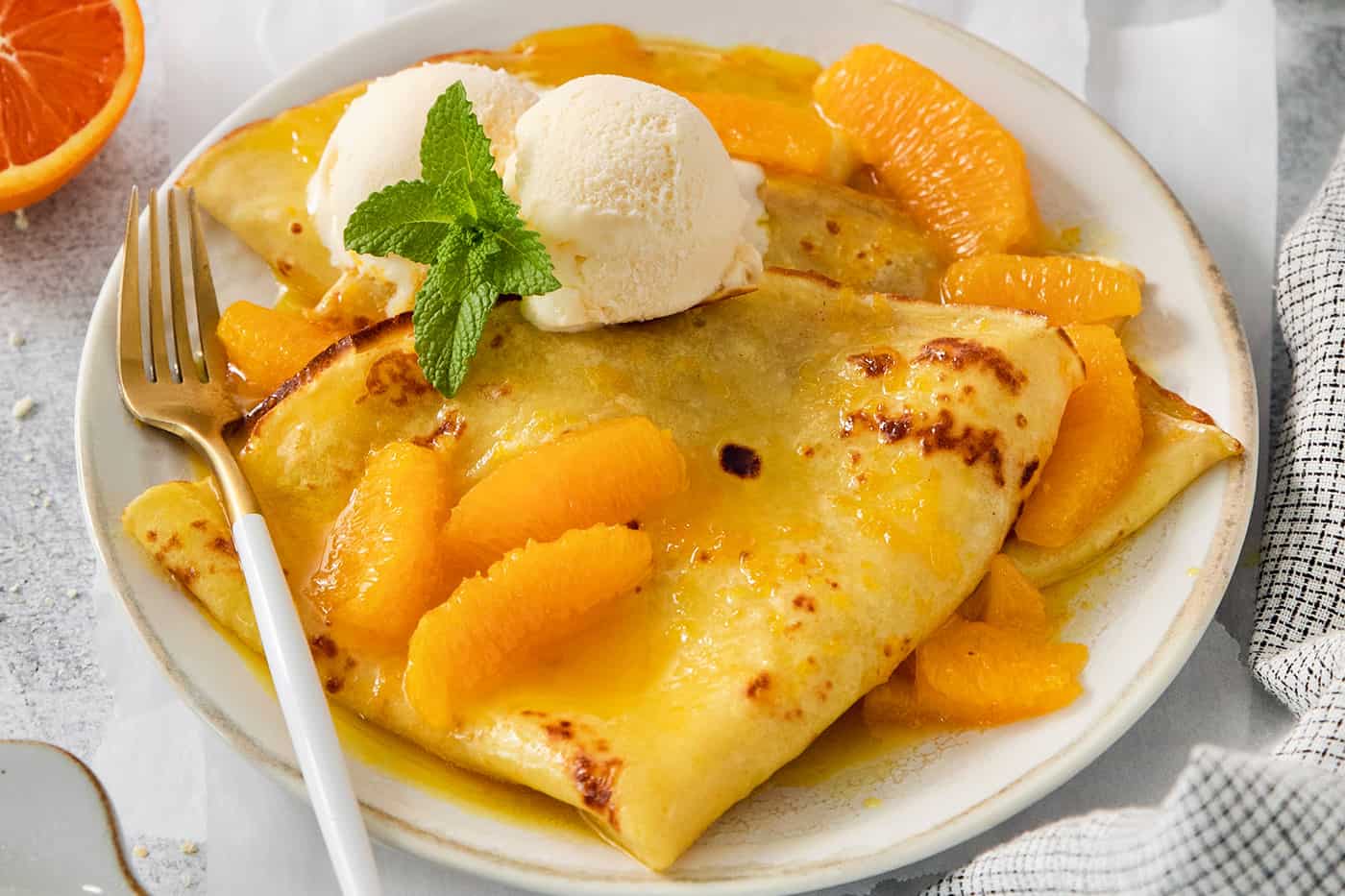 A fork rests on the side of a plate of crepes Suzette.