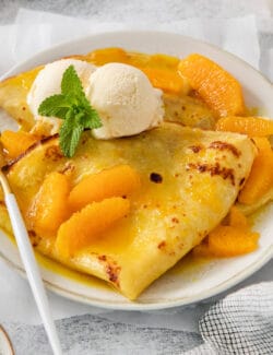 A fork rests on the side of a plate of crepes Suzette.