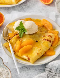 A fork rests on the side of a plate of crepes Suzette.