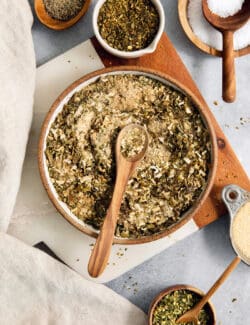 A big bowl of green taco seasoning with a wooden spoon resting in it.