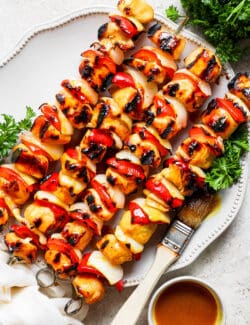 A serving platter of honey mustard chicken kabobs on skewers.