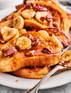French toast with bananas foster sauce, layered on a white platter