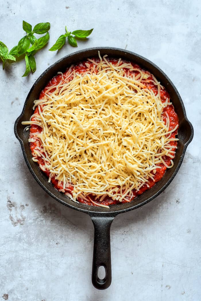 Mozarella is scattered over the sauce.
