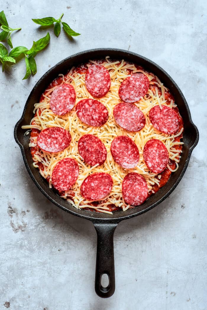Pepperoni is arranged on top of the cheese.