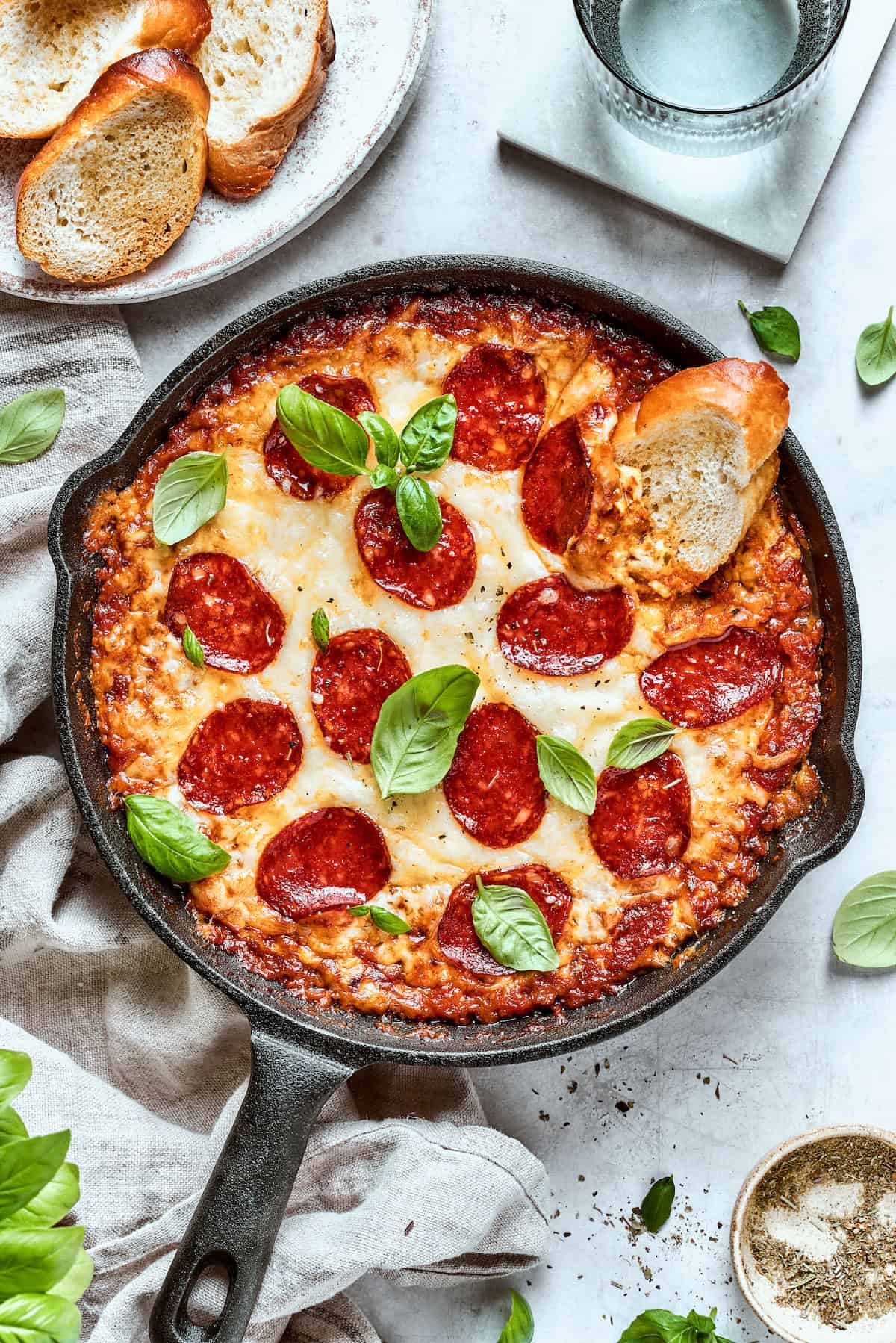 Creamy Pizza Dip is the best appetizer or snack! A blend of four cheeses and savory tomato sauce combines for an ultra-scoopable, gooey dip. A slice of bread is dipped into a pan of pizza dip.