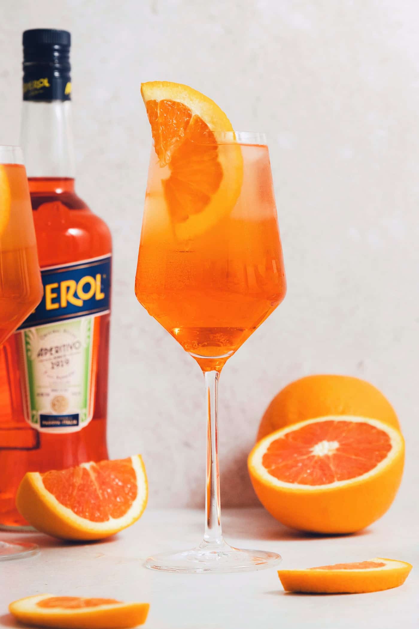 This classic Aperol spritz recipe is my take on an Italian aperitivo and makes a refreshing cocktail out of just four ingredients. A glass of orange Aperol spritz is surrounded by orange wedges next to a bottle of Aperol.