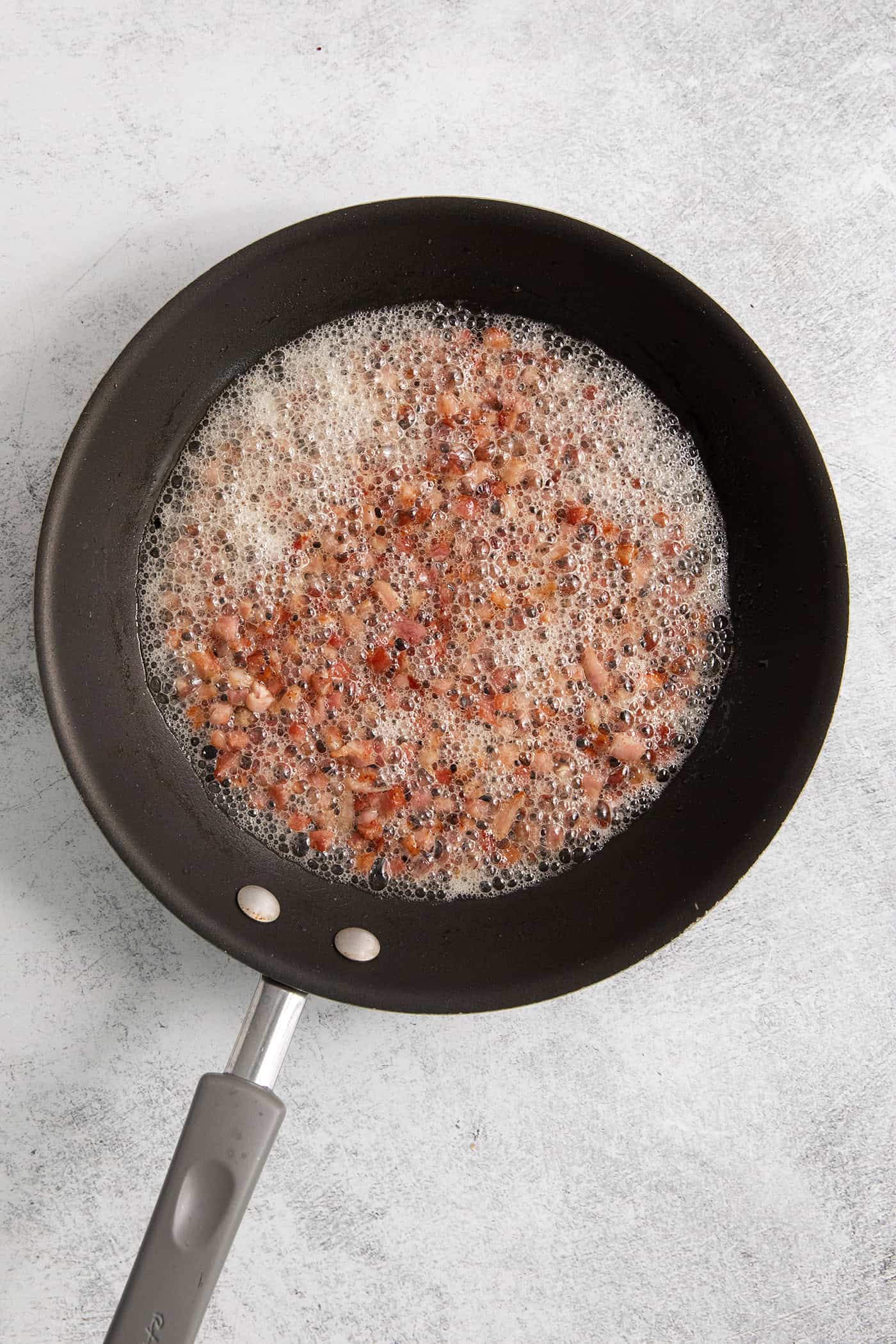 Chopped pancetta browns in a skillet.
