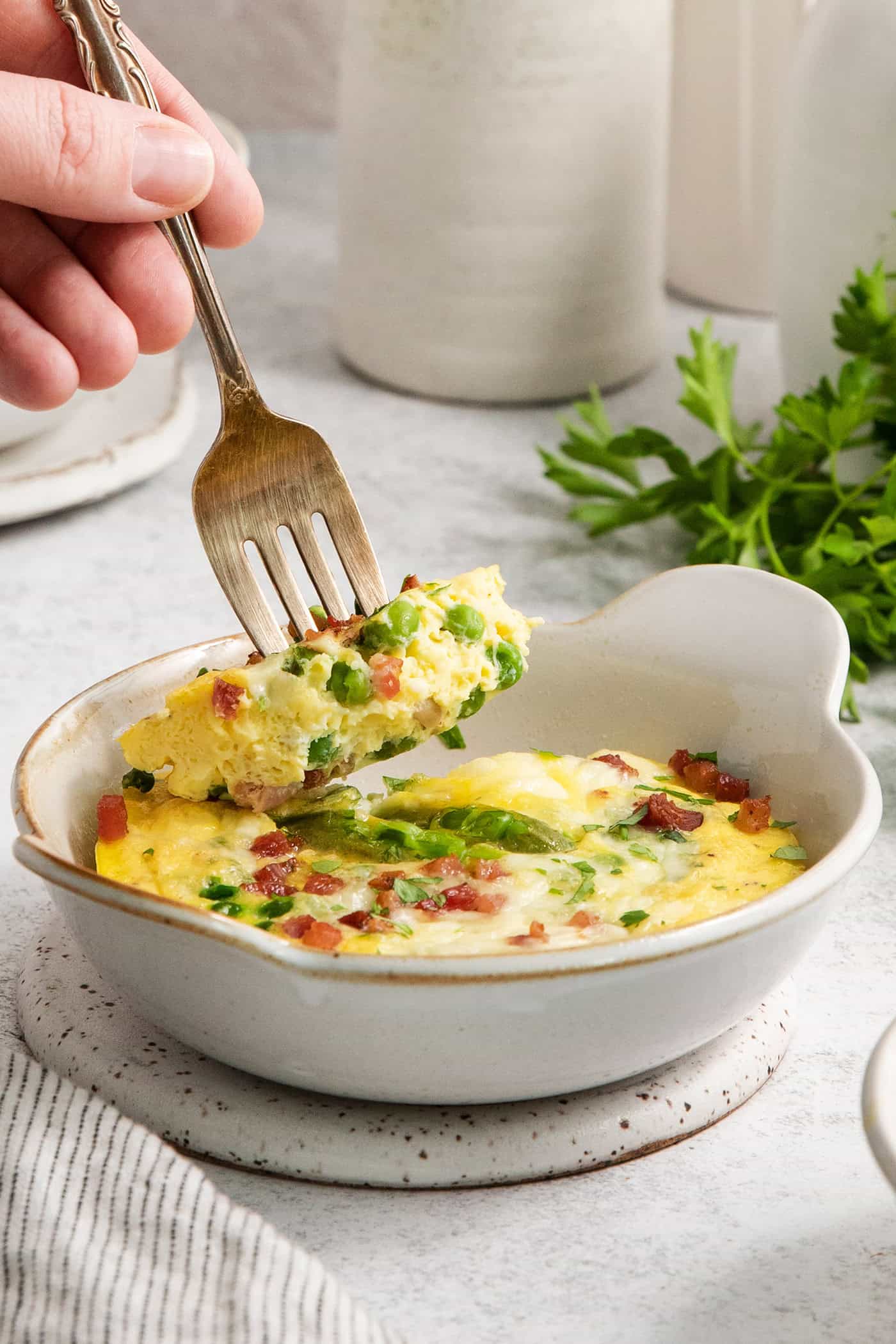 A fork picks up a piece of a ramekin of baked eggs.