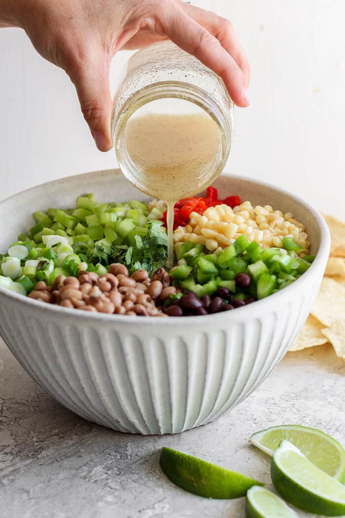 Dressing is poured over a bowl of cowboy caviar.