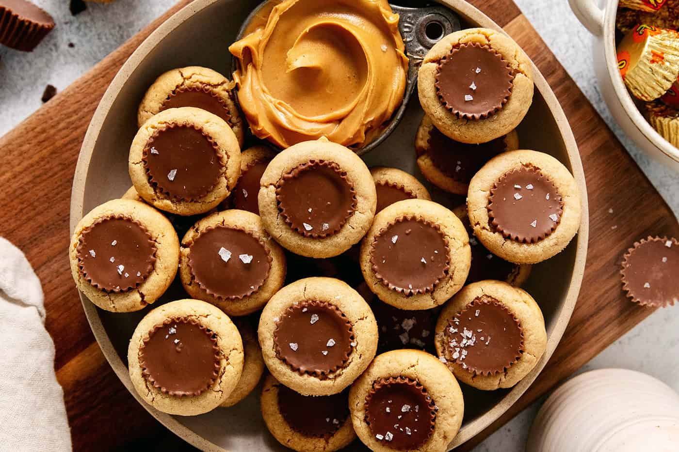 Peanut butter cup cookies with a dish of creamy peanut butter next to them are served in a bowl.