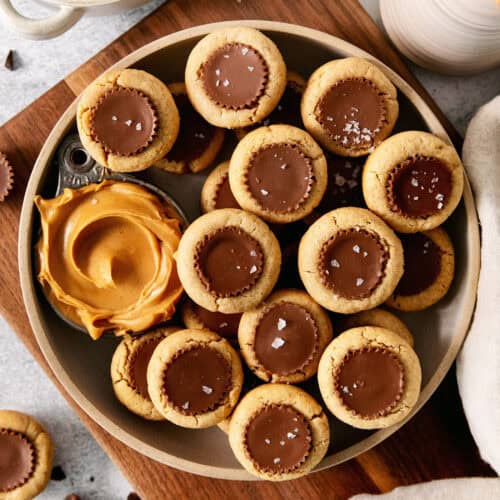 Peanut butter cup cookies with a dish of creamy peanut butter next to them are served in a bowl.
