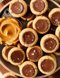 Peanut butter cup cookies with a dish of creamy peanut butter next to them are served in a bowl.