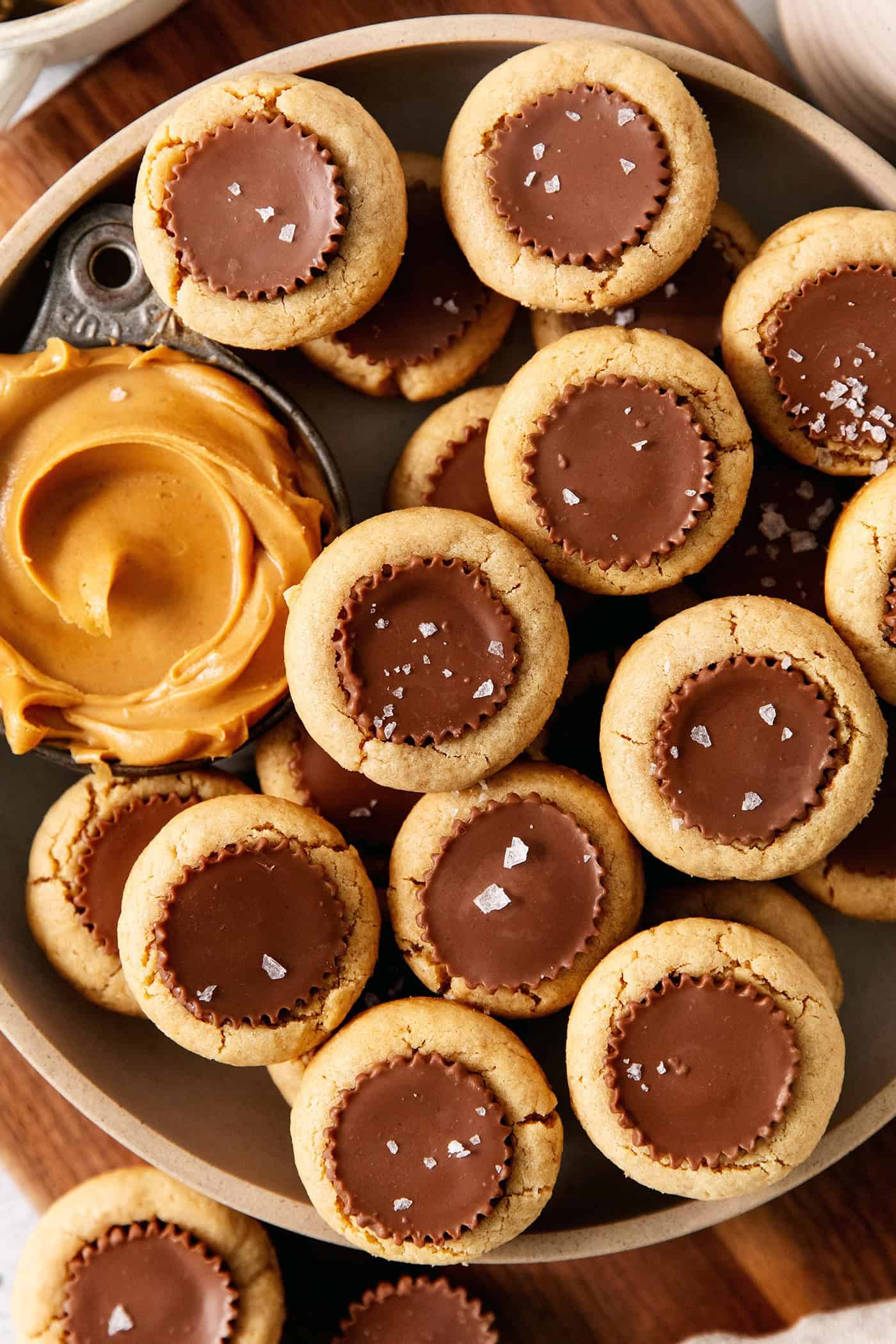 Peanut butter cup cookies with a dish of creamy peanut butter next to them are served in a bowl.