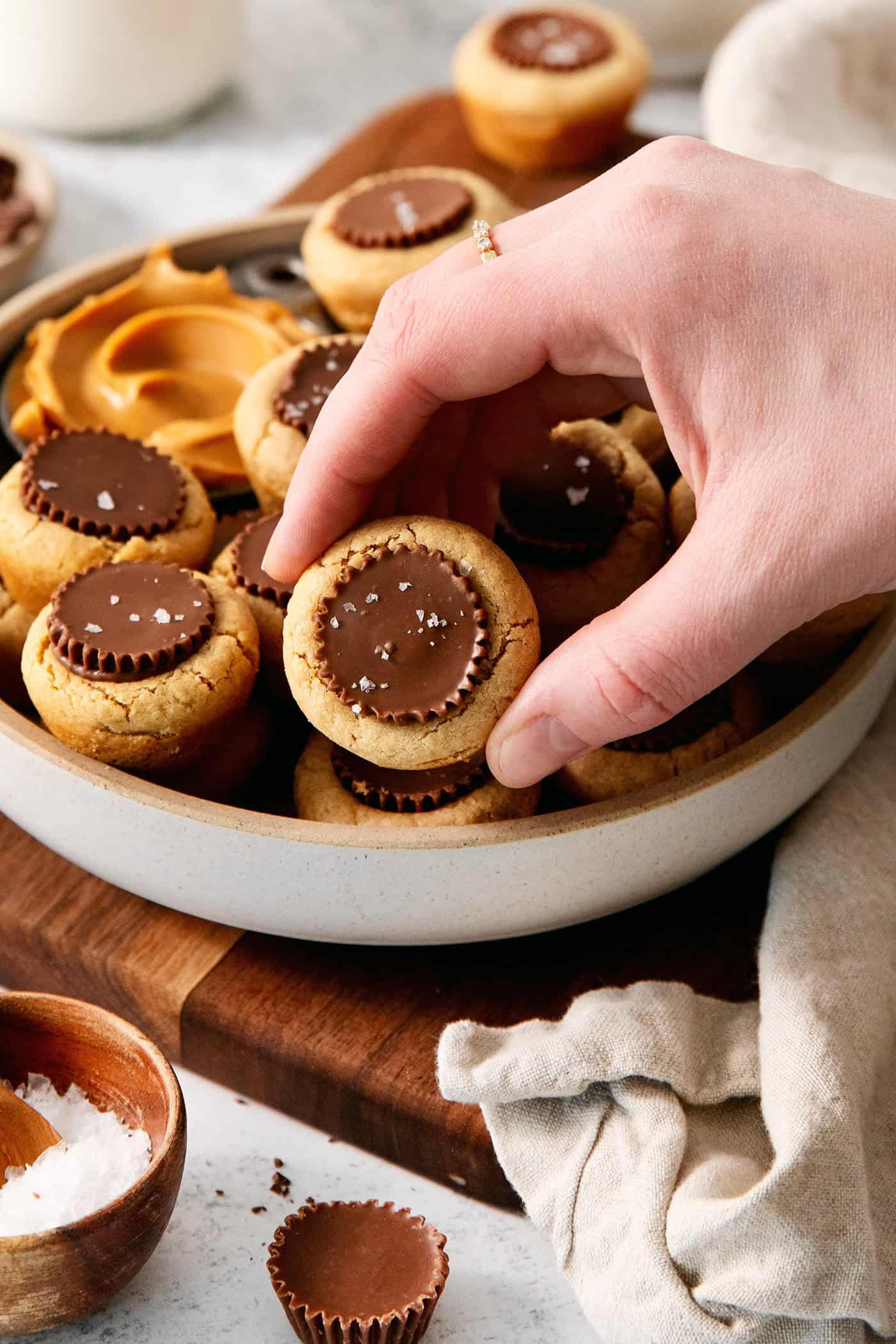 A hand lifts out a peanut butter cup cookie from a bowl.