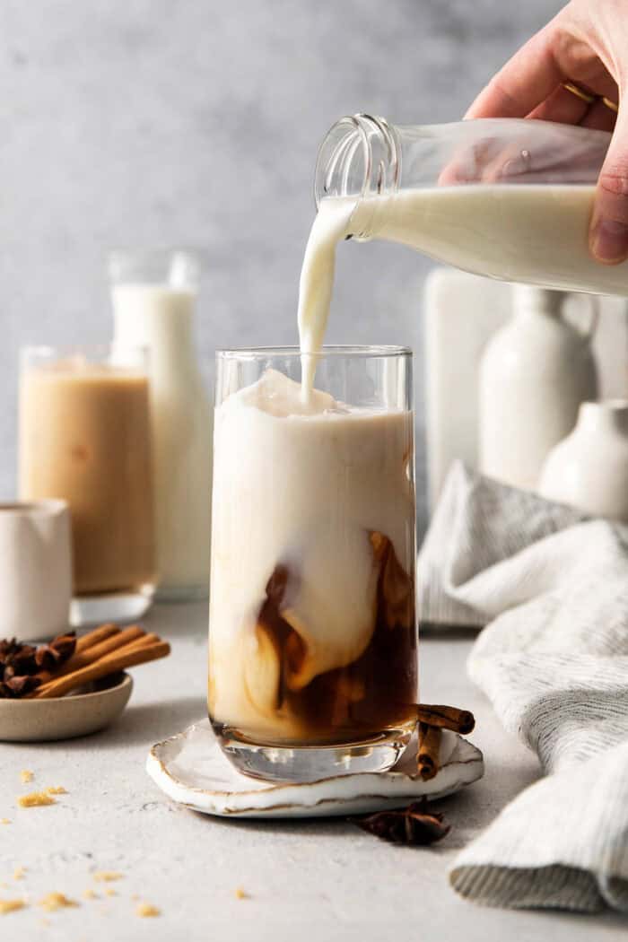 Milk is poured into the glass with the chai and ice.