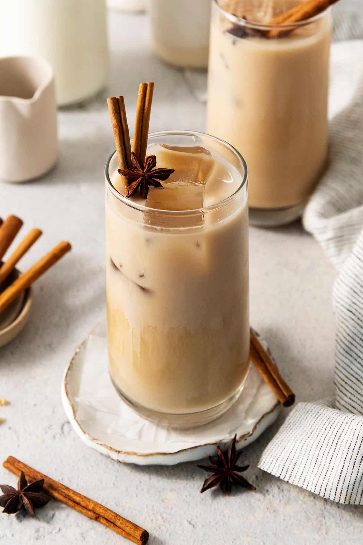 Cinnamon sticks and star anise garnish tall glasses of iced chai latte.