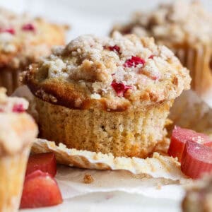 side view of rhubarb muffins, one with the paper liner pulled away from the muffin