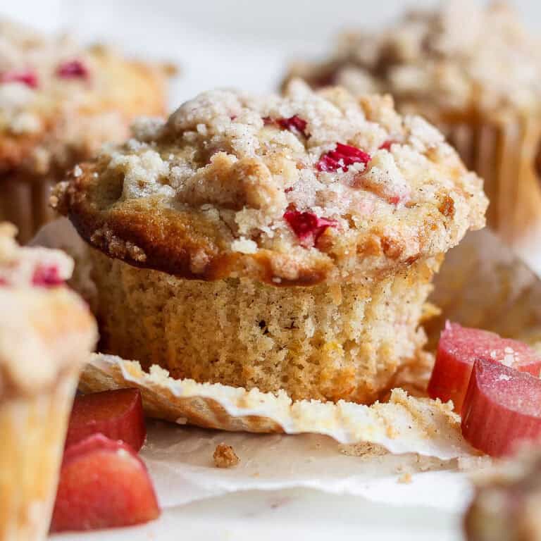 side view of rhubarb muffins, one with the paper liner pulled away from the muffin